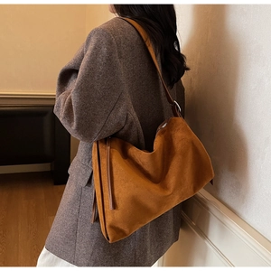 Side view of a vintage caramel suede tote bag worn over the shoulder in a minimalist room
