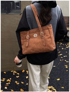 Detail of vintage brown tote bag featuring silver twist lock and retro leather texture