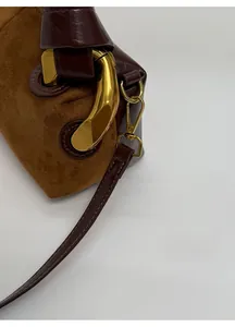 Macro detail of retro suede and leather bag with oversized antique gold hardware buckles