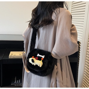Détail du sac à bandoulière noir en peluche avec petit chien jaune et charme en os