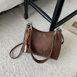 Detail of vintage brown leather handbag with wooden bead pendant and silver metal clasp