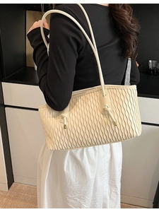 Sac à bandoulière beige chic avec texture plissée et détails dorés sur un mannequin