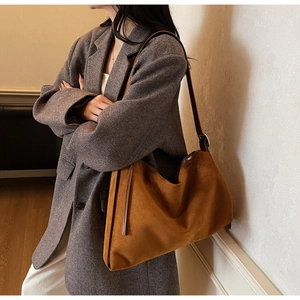 Close-up of caramel suede tote bag with dark brown leather straps on a professional model
