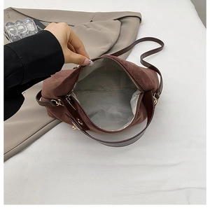 Close-up of brown suede Boston bag with smooth zipper and spacious grey interior
