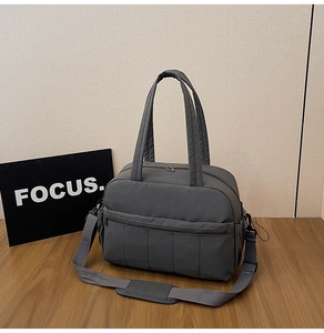 Detail of grey travel bag featuring sturdy handles and adjustable shoulder strap padding