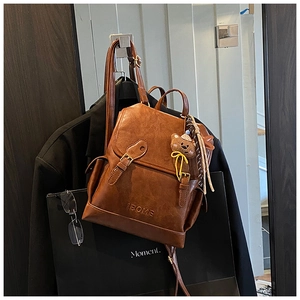 Close-up of vintage brown leather backpack with embossed iBOME logo and cute bear charm
