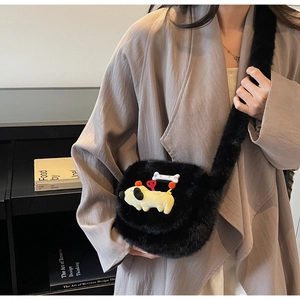 Détail d'un sac en peluche noire avec une poupée chien jaune et des breloques étoiles