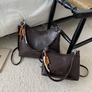 Detail of dark brown faux leather hobo bags in two sizes with wooden bead tassel accents