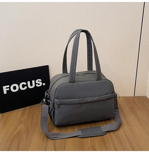 Detail of grey travel bag featuring wide adjustable strap and zippered front pocket