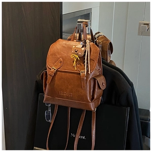 Detail of vintage brown leather backpack featuring BOME embossed logo and cute bear charm