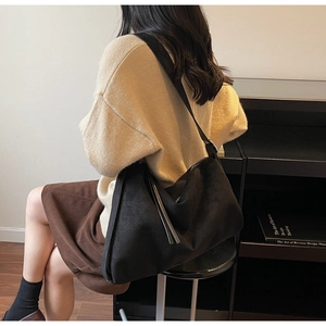 Detailweergave van een zwarte oversized hobo-tas met een brede schouderband op een model