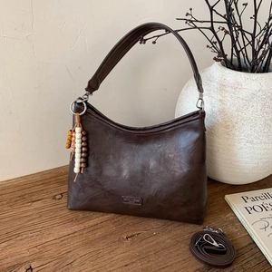 Detail view of brown faux leather bag texture with beads and adjustable shoulder strap