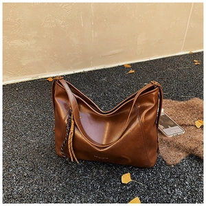 Vue détaillée du sac cabas marron foncé en similicuir avec nœuds tressés sur sol extérieur