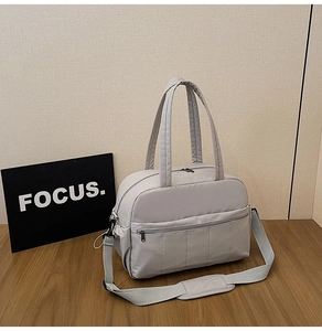 Detail of light grey travel bag featuring durable handles and adjustable shoulder strap