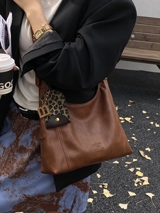 Braune Vintage-Ledertasche mit Leoparden-Anhänger und goldenen Akzenten am Modell
