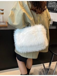 White faux fur shoulder bag with gold chain strap shown on model in a minimalist cafe