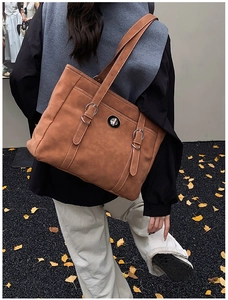 Detail view of brown tote bag with white contrast stitching and round metal twist-lock