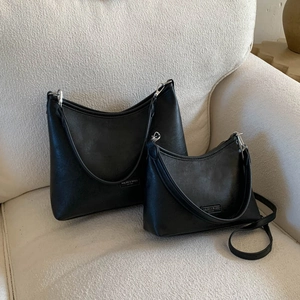 Detail of two-piece black matte leather handbag set with delicate texture on sofa