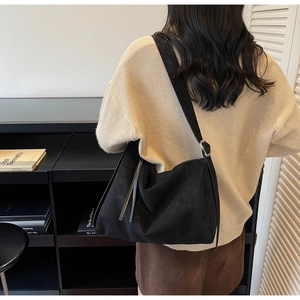 Detail of adjustable strap and silver buckle on black faux suede crossbody bag