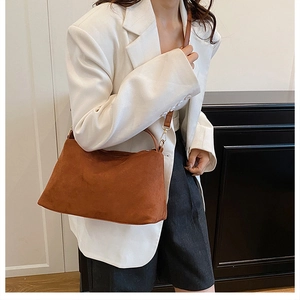 Detail of a brown matte suede tote bag with adjustable shoulder strap and gold hardware