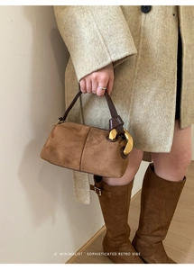 Detail of a brown suede retro pillow bag with a large gold ring buckle for women