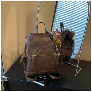 Detail of vintage brown leather backpack with iBOMB logo and cute bear charm