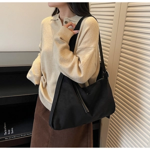 Detail shot of a black hobo bag with matte finish on a model in a cozy urban setting