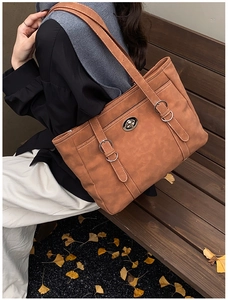 Close-up of brown suede tote bag with silver buckles and white contrast stitching detail