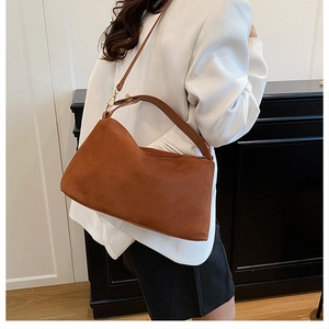 Detail view of brown frosted suede pillow bag with golden hardware and adjustable strap