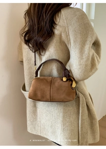 Close-up of caramel suede Boston bag with leather handles and gold-tone hardware detail