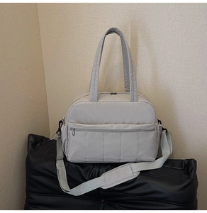 Detail of light grey travel bag showing nylon fabric texture and adjustable shoulder strap