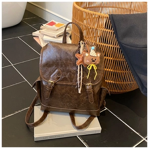 Close-up of vintage brown PU leather backpack with decorative straps and bear charm