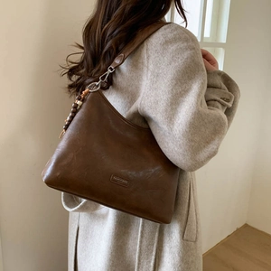 Detail of vintage dark brown tote bag with wide strap and colorful wooden bead pendant