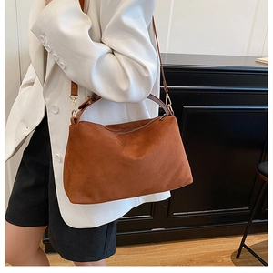 Brown suede tote bag detail with adjustable leather strap and golden hardware accents