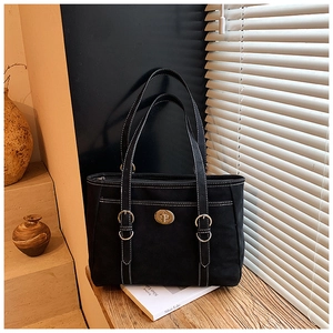 Close-up of black tote bag with white contrast stitching and a vintage gold twist lock