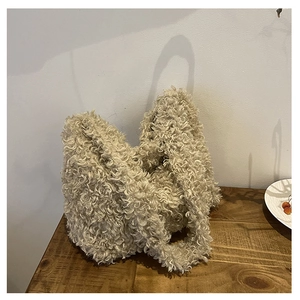 Close-up of fluffy beige faux fur tote bag texture on a vintage wooden table surface
