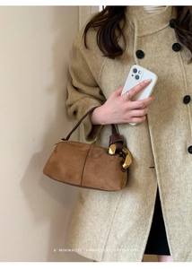 Macro shot of brown suede handbag featuring large golden metal ring and premium texture