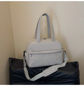 Detail view of light grey travel bag with multiple pockets and adjustable shoulder strap