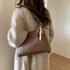 Detailed close-up of dark brown vintage shoulder bag with wooden beads tassel ornament