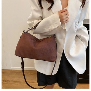 Close-up of a dark brown suede crossbody bag with gold zipper and adjustable strap