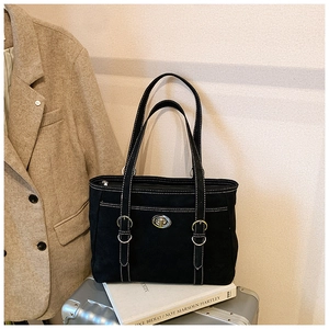 Detail of black tote bag with white contrast stitching and metallic turn-lock closure