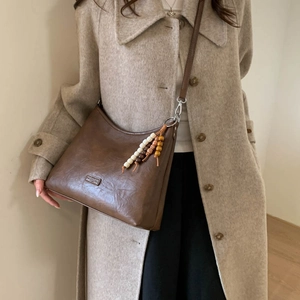 Detail of vintage brown shoulder bag with natural texture and decorative wooden beads