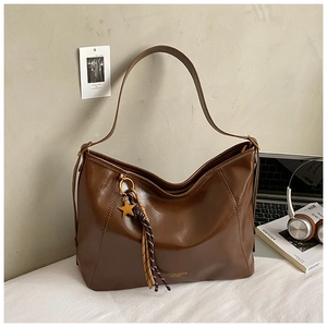 Gros plan du sac en cuir marron avec pendentif étoile, pompons et logo doré élégant