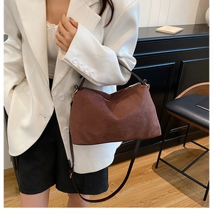 Detail of soft dark brown suede hobo bag with a gold zipper and smooth leather strap