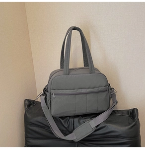 Detailed view of dark grey travel bag showing water-resistant nylon texture and metal zippers