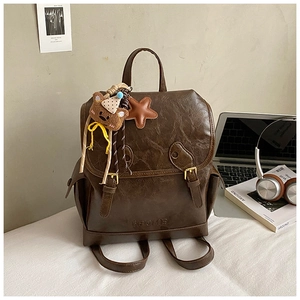 Detail of retro dark brown PU leather backpack with vintage metal clasp and cute plush charms