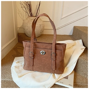 Detail of caramel oil-wax leather tote bag showing white stitching and metal twist lock