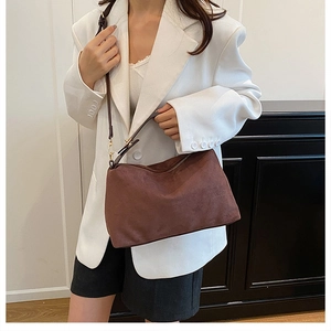 Detail of a brown matte suede tote bag styled with a white blazer for a chic office look