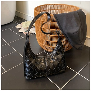 Detailaufnahme der schwarzen geflochtenen Ledertasche mit glänzendem Finish und Reißverschluss