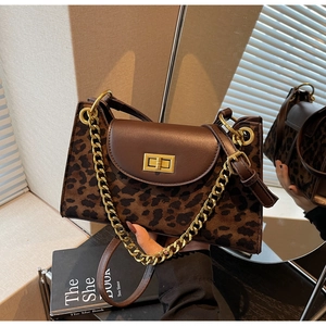 Detail of leopard print handbag with brown leather flap and gold chain strap in hand